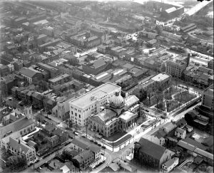 A black and white aerial photograph of downtown Norristown in 1930. The montgomery county court house, a greek revival building with a central dome, is prominently featured.