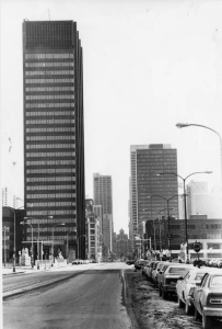 A black and white photograph of the PECO building, a modernist high rise with black cladding and a prominent electronic billboard atop it.